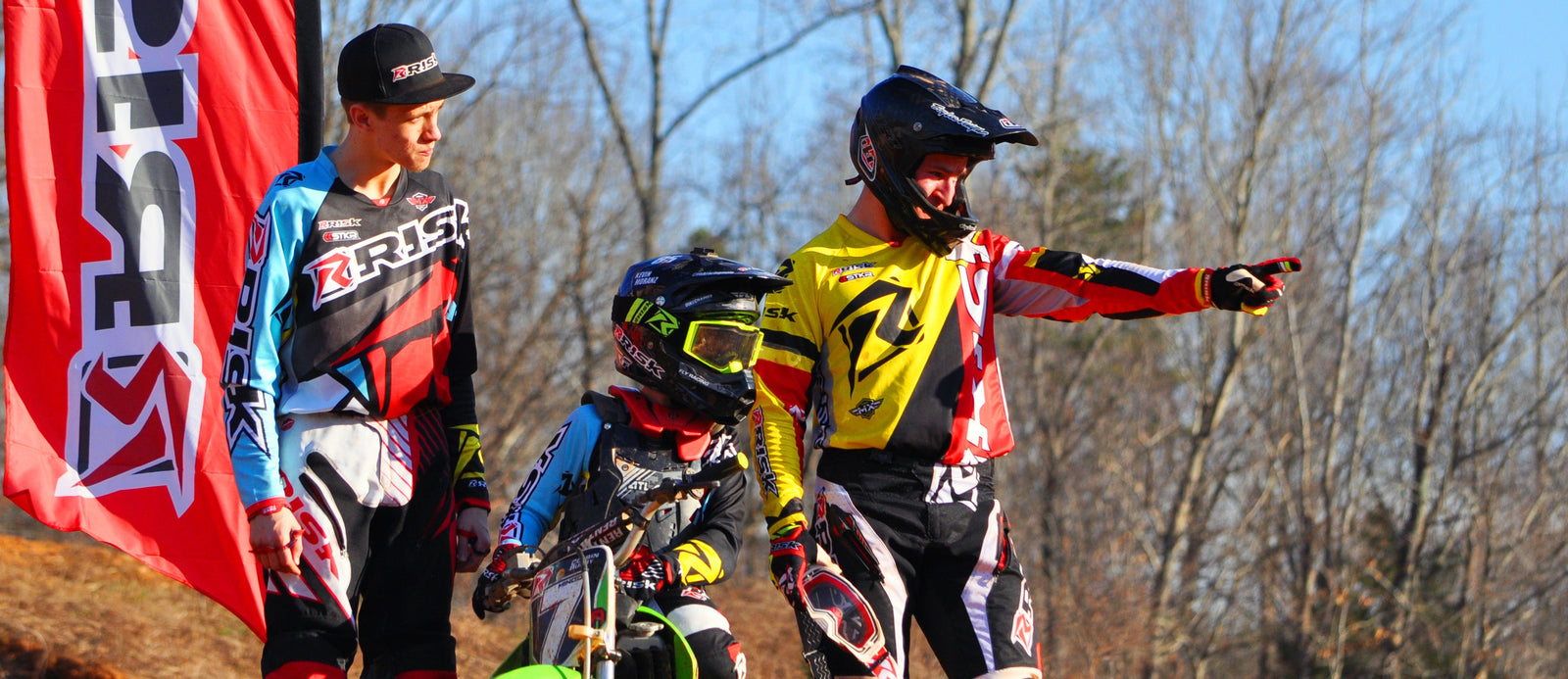 Three members of the risk racing team standing atop a track feature discussing another track feature.
