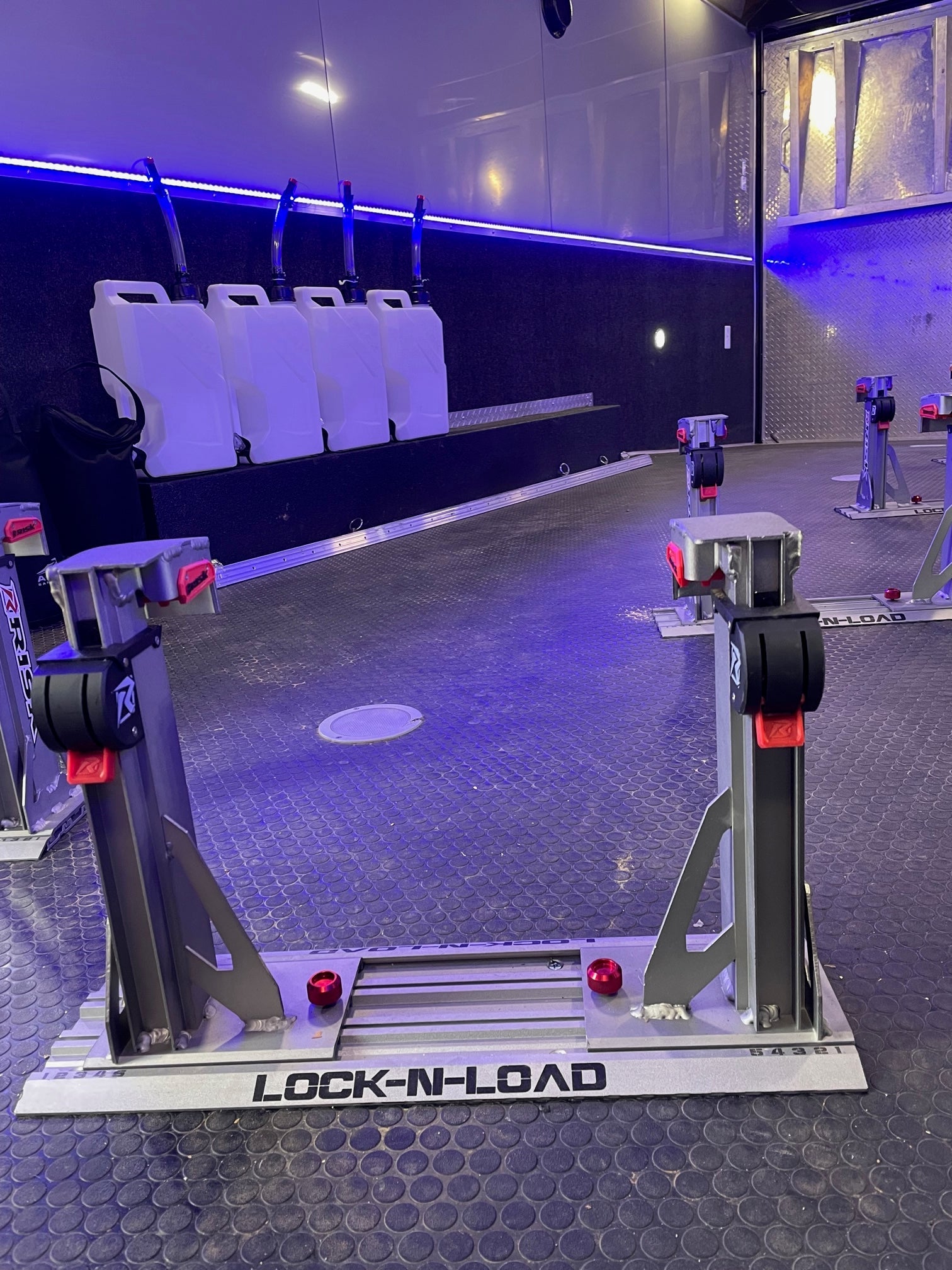 enclosed moto trailer equipped with multiple lock-n-load dirt bike transport systems and multiple EZ utility jugs with hose benders