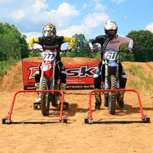 Oudoor picture of two MX riders lined up at Holeshot Pro Gates aimed right at camera